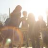 silhouette of people standing on brown wooden fence during sunset